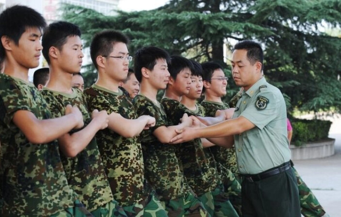 Estudiantes practican la marcha bajo la supervisión de un soldado del Ejército Popular de Liberación durante la primera semana de servicio militar en una base de Hefei, provincia oriental china de Anhui, el 5 de agosto de 2010. (AFP/Getty Images). 

