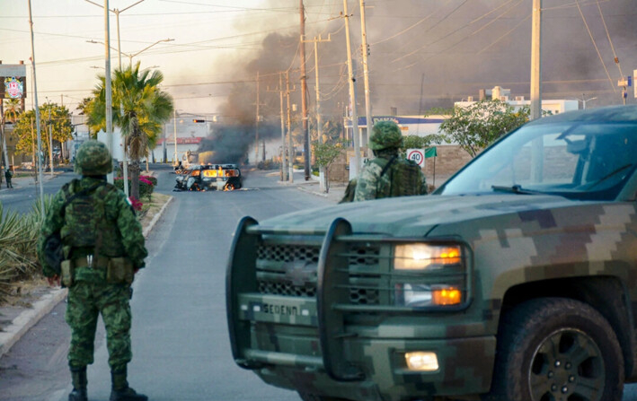 Soldados mexicanos hacen guardia cerca de vehículos en llamas en una calle durante un operativo para arrestar al hijo de Joaquín "El Chapo" Guzmán, Ovidio Guzmán, en el estado de Sinaloa, México, el 5 de enero de 2023. (Juan Carlos Cruz/ AFP vía Getty Images)