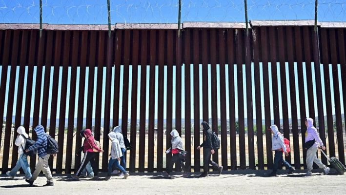 Inmigrantes ilegales caminan por el lado estadounidense del muro fronterizo en Jacumba Hot Springs, California, tras cruzar desde México el 5 de junio de 2024. (Frederic J. Brown/AFP vía Getty Images)