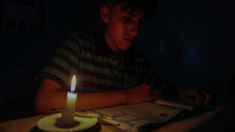 Fotografía de archivo en donde se ve a un estudiante que lee un texto a la luz de una vela en Quito (Ecuador). EFE/José Jácome