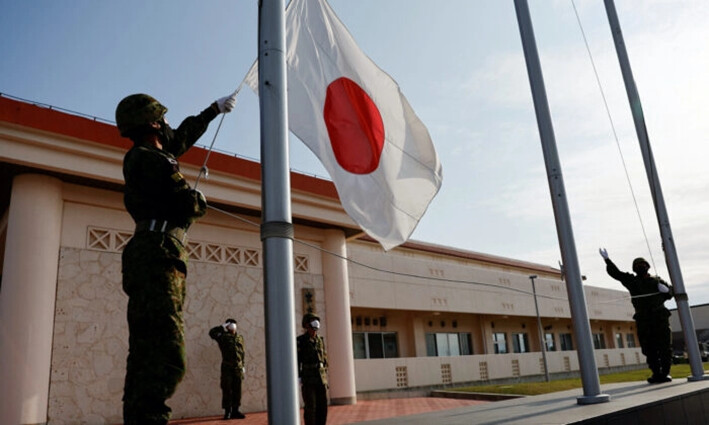 Miembros de la Fuerza Terrestre de Autodefensa de Japón (JGSDF) bajan la bandera nacional japonesa al anochecer, en el campamento Miyako de la JGSDF en la isla Miyako, prefectura de Okinawa, Japón, el 20 de abril de 2022. (Issei Kato/Reuters)