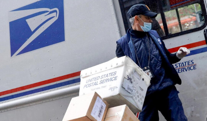 Un empleado del Servicio Postal de EE. UU. descarga paquetes de su camión en la ciudad de Nueva York el 13 de abril de 2020. (Mike Segar/Reuters)