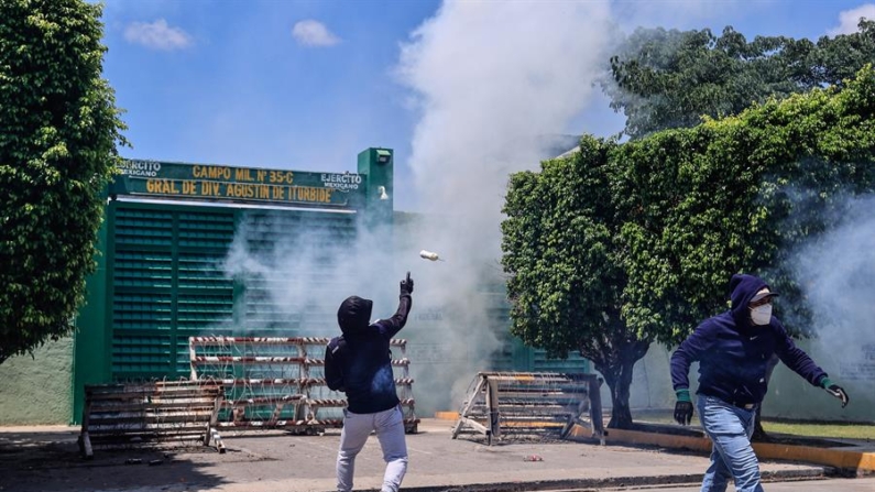 Manifestantes encapuchados protestan el 20 de septiembre de 2024 afuera de una de las entradas del Batallón 27 de Infantería, en el municipio de Iguala, en el estado de Guerrero (México). EFE/David Guzmán