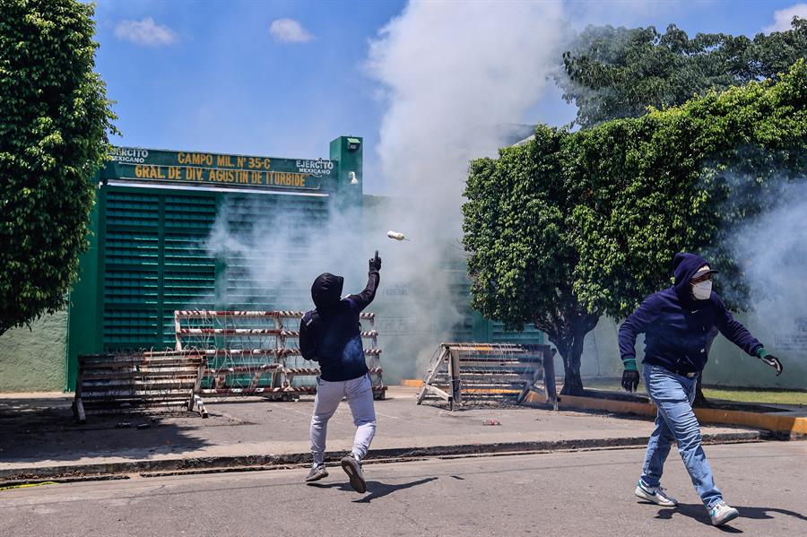 Activistas de Ayotzinapa lanzan petardos y causan incendios frente al Ejército mexicano