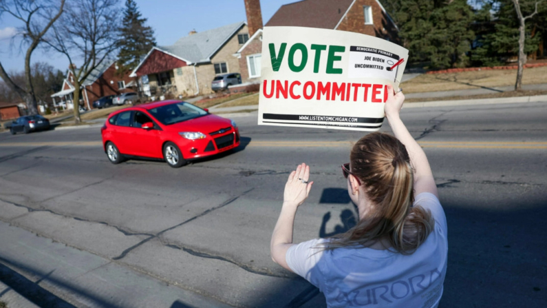 Una votante demócrata no comprometida con el presidente Joe Biden se concentra a las puertas de un colegio electoral mientras pasa un coche en la Oakman Elementary School de Dearborn, Michigan, el 27 de febrero de 2024. (Kevin Dietsch/Getty Images)