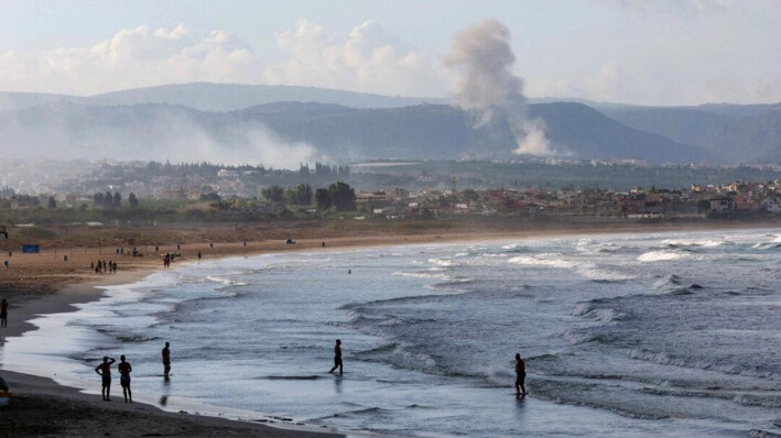 Varias personas caminan por una playa mientras el humo se eleva al fondo en el lado libanés de la frontera con Israel, visto desde Tiro, sur del Líbano, el 22 de septiembre de 2024 Aziz Taher/Reuters