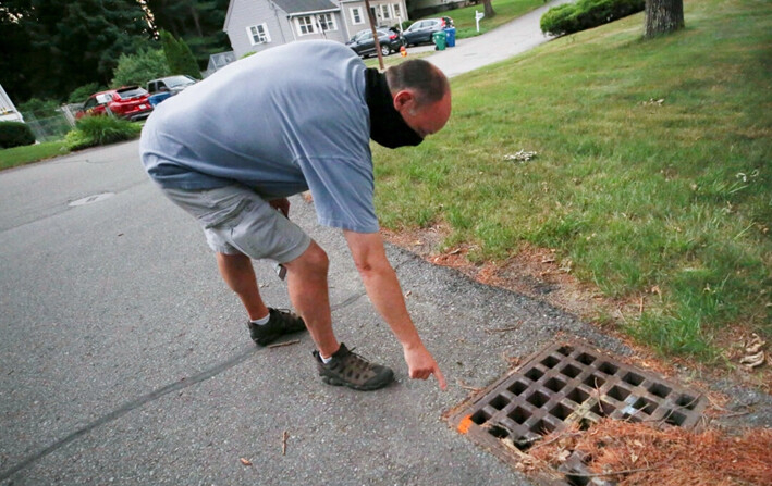 Chris Gagnon, gerente de operaciones de campo del Proyecto de Control de Mosquitos de East Middlesex, señala con un marcador de pintura que se ha tratado un desagüe pluvial para controlar los mosquitos en Burlington, Massachusetts, el 8 de julio de 2020. (Charles Krupa/AP Photo)