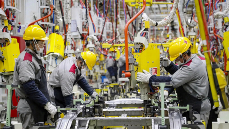 Empleados trabajando en una cadena de montaje de automóviles en una fábrica de Beijing Automotive en Qingdao, en la provincia oriental china de Shandong, el 14 de enero de 2023. (STR/AFP vía Getty Images)