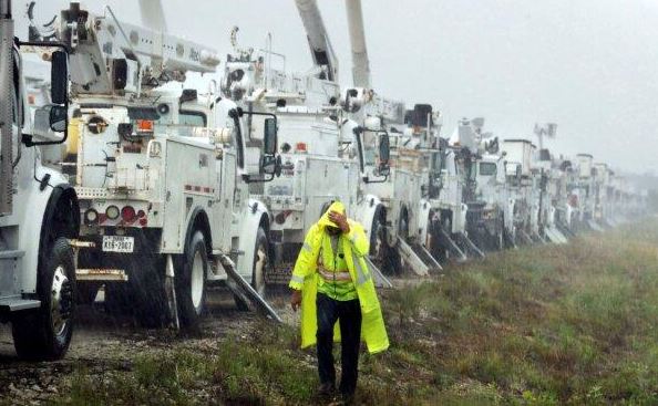 Charles Starling, un técnico de líneas del Equipo Fishel, recibe una lluvia torrencial mientras camina junto a una hilera de camiones de líneas eléctricas en un campo en The Villages, Florida, en preparación para los daños del huracán Helene, el 26 de septiembre de 2024. (Stephen M. Dowell/Orlando Sentinel vía AP)