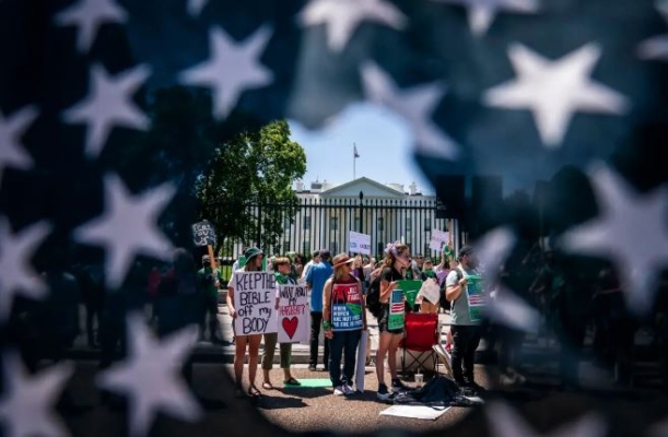 Activistas por el derecho al aborto con una bandera estadounidense rasgada durante una concentración frente a la Casa Blanca en Washington, el 4 de julio de 2022. (Nathan Howard/Getty Images)