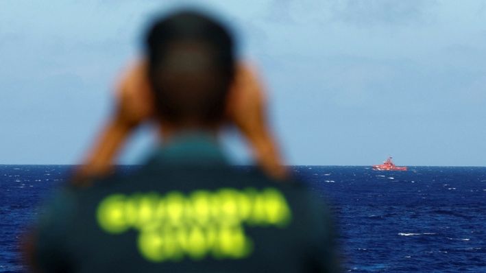 Un agente de la Guardia Civil vigila un barco de rescate que busca posibles supervivientes tras el naufragio de una embarcación de madera con inmigrantes cerca del puerto de La Restinga, en la isla de El Hierro, España, el 28 de septiembre de 2024. (Borja Suárez/Reuters)