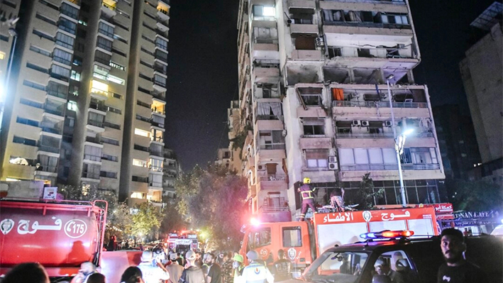 Los bomberos se reúnen en el lugar de un edificio de apartamentos alcanzado por un ataque aéreo israelí en el distrito de Cola de Beirut, Líbano, el 30 de septiembre de 2024. (FADEL ITANI/AFP vía Getty Images)