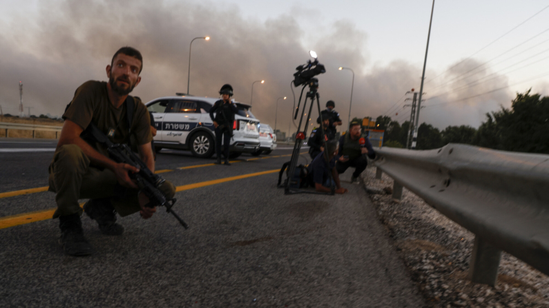 Periodistas y policías israelíes se cubren durante un ataque con cohetes desde el sur de Líbano, en los Altos del Golán anexionados por Israel, el 9 de julio de 2024, en medio de los continuos enfrentamientos transfronterizos entre tropas israelíes y combatientes de Hezbolá. (Foto de JALAA MAREY/AFP vía Getty Images)