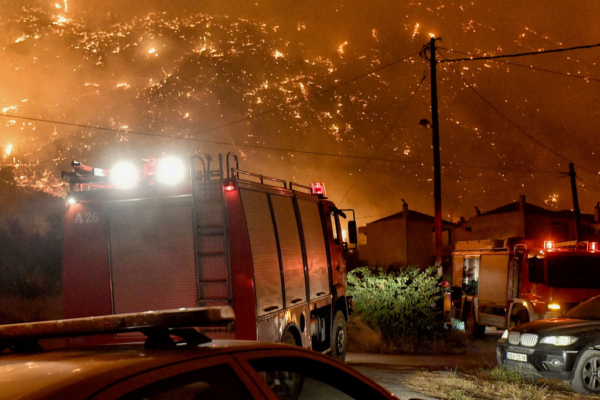 Vehículos de extinción de incendios aparcados en el pueblo de Ano Loutro, al sur de Atenas, mientras un incendio forestal se acerca a las casas el 30 de septiembre de 2024. (Valerie Gache / AFP vía Getty Images)