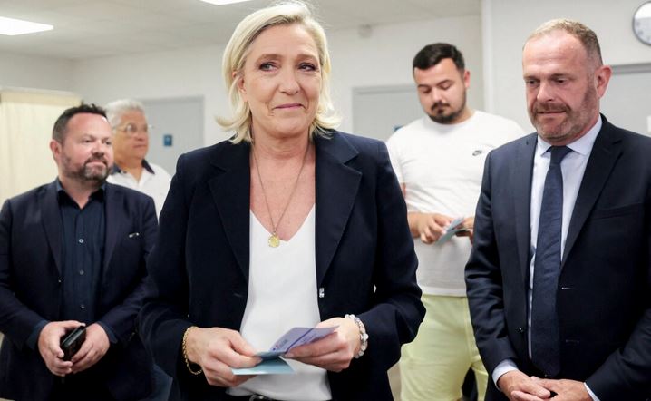 La líder del partido francés Agrupación Nacional, Marine Le Pen (C), sostiene las papeletas junto al alcalde de Henin-Beaumont, Steeve Briois (D), antes de votar en la primera vuelta de las elecciones parlamentarias en Henin-Beaumont, norte de Francia, el 30 de junio de 2024. (Francois Lo Presti/AFP vía Getty Images)