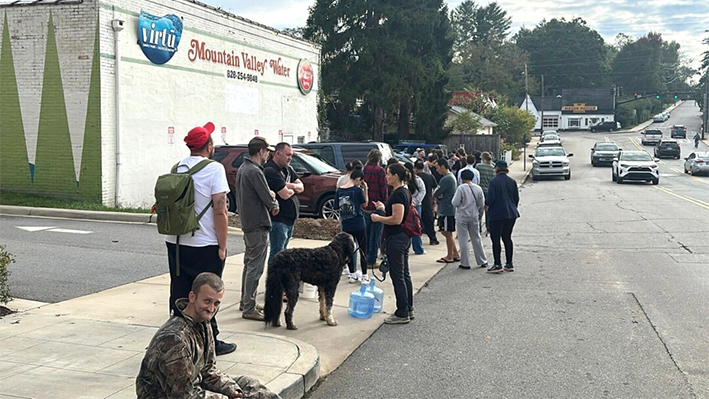 La gente espera para recoger agua en Mountain Valley Water tras el paso del huracán Helene en West Asheville, Carolina del Norte, el 30 de septiembre de 2024. (Jeffrey Collins/Foto AP)