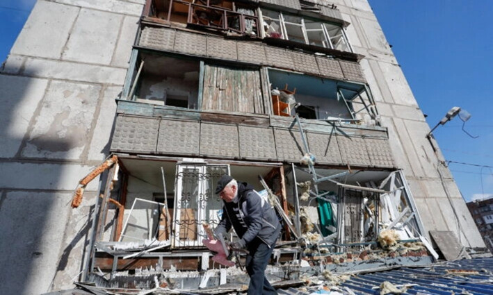 Un hombre retira escombros del exterior de un edificio residencial dañado por los bombardeos en la ciudad de Makiivka, Ucrania, el 16 de marzo de 2022. (Alexander Ermochenko/Reuters)