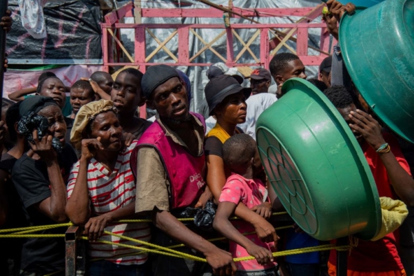 La gente espera para una distribución de alimentos en un campamento de desplazados en el Liceo Marie Jeanne en Puerto Príncipe el 30 de septiembre de 2024. El Consejo de Seguridad de la ONU prorrogó el lunes su autorización a la misión policial multinacional en Haití, devastada por la delincuencia. (Clarens Siffroy/AFP vía Getty Images)