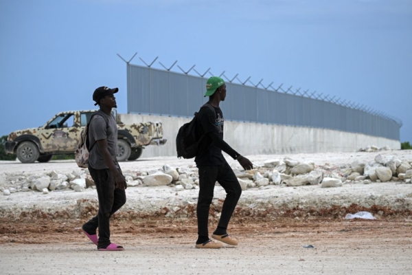 Ciudadanos haitianos pasan por delante del muro fronterizo que se está construyendo en la frontera entre República Dominicana y Haití, en Pedernales, República Dominicana, el 15 de mayo de 2024. (Federico Parra / AFP via Getty Images)