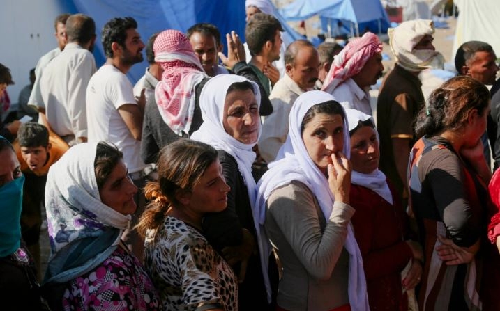 Iraquíes desplazados de la comunidad yazidí se reúnen para recibir ayuda humanitaria en el campamento de Nowruz, en Derike, Siria, el 12 de agosto de 2014. (AP Photo/ Khalid Mohammed)