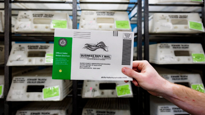 El director de una Junta Electoral, Tyler Burns, sostiene una papeleta de prueba durante una demostración de procesamiento de papeletas de voto por correo en la oficina de la Junta, en Doylestown, Pensilvania, el 30 de septiembre de 2024. (Hannah Beier/Getty Images)