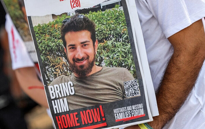 Omri Shtivi, hermano del rehén israelí Idan Shtivi (en la foto), sostiene un cartel que lo identifica durante una manifestación de las familias de los rehenes tomados cautivos en la Franja de Gaza desde los ataques del 7 de octubre, cerca del Kibbutz Nirim, en el sur de Israel, el 29 de agosto de 2024. (Jack Guez/AFP vía Getty Images)