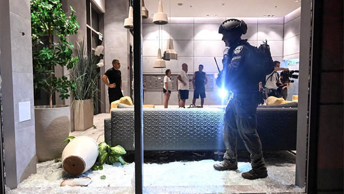 Un agente de policía israelí inspecciona los daños en un edificio residencial causados por un cohete disparado hacia Israel desde Líbano, en medio de las hostilidades transfronterizas entre Hezbolá e Israel, en Haifa, Israel, el 7 de octubre de 2024. (Rami Shlush/Reuters)