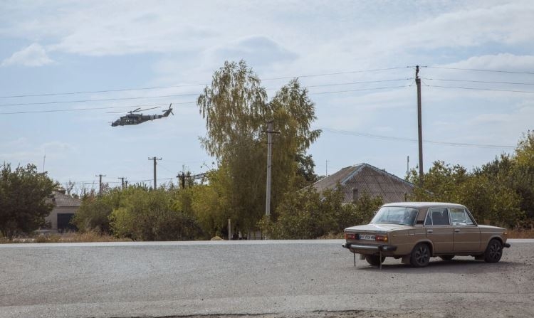 Un helicóptero militar ucraniano vuela mientras un coche circula por una carretera en una zona de invasión rusa, en la región de Donetsk, Ucrania, el 4 de octubre de 2024. (Roman Pilipey/AFP vía Getty Images)