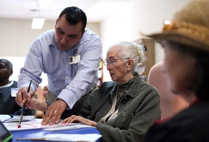 Un trabajador ayuda a una anciana durante una sesión de actividades en una guardería de California, el 10 de febrero de 2011. (Justin Sullivan/Getty Images)