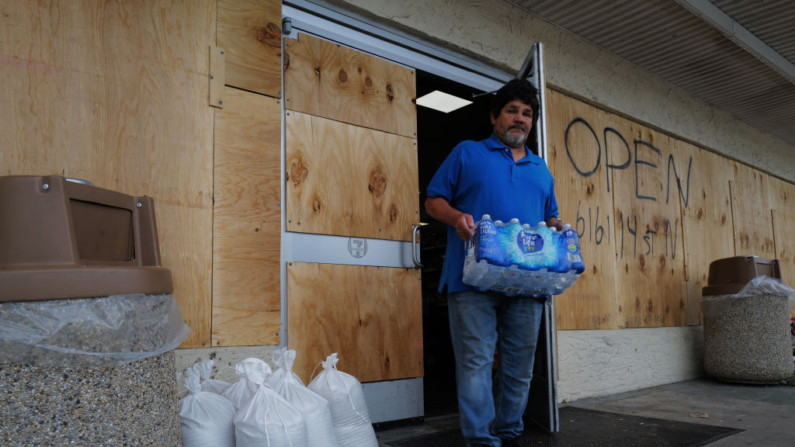 La gente entra y sale de una tienda 7-11 tapiada mientras el estado se prepara para la llegada del huracán Milton el 8 de octubre de 2024, en San Petersburgo, Florida. (Spencer Platt/Getty Images)