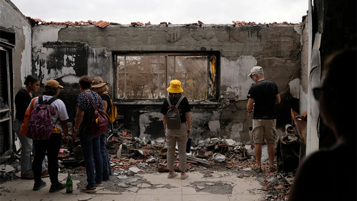 El 7 de octubre de 2024, cuando Israel conmemoraba el primer aniversario del ataque de Hamás contra Israel, varias personas permanecen junto a una casa destrozada por la guerra en el kibutz Be'eri, una granja comunal israelí situada en la frontera con Gaza. (AP Photo/Ohad Zwigenberg)