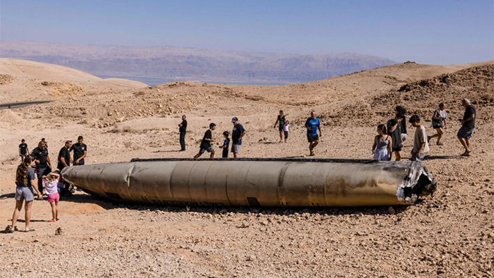 Un grupo de personas visita los restos de un misil iraní en el desierto del Néguev, cerca de Arad, tras un ataque con misiles iraníes contra Israel. (Menahem Kahana/AFP)