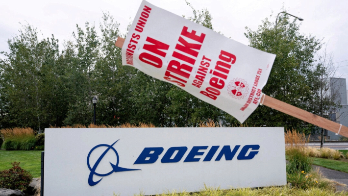 Un cartel de huelga cuelga de un poste cerca de un cartel de Boeing mientras trabajadores de la fábrica de Boeing y simpatizantes se reúnen en una línea de piquete durante el tercer día de huelga en Renton, Washington, el 15 de septiembre de 2024. (David Ryder/Reuters)