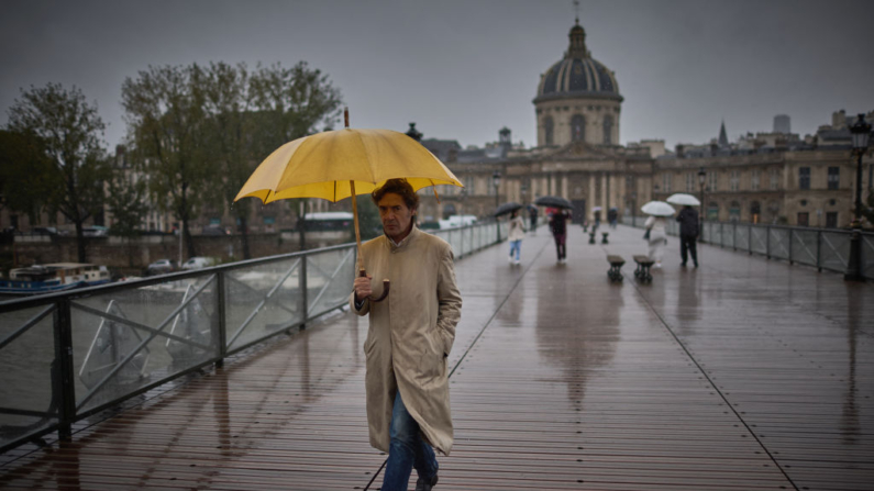 Un hombre se refugia bajo un paraguas mientras camina por el puente Pont des Arts mientras los restos del huracán Kirk provocan fuertes lluvias en el centro de París (Francia), el 9 de octubre de 2024. (Kiran Ridley/AFP vía Getty Images)