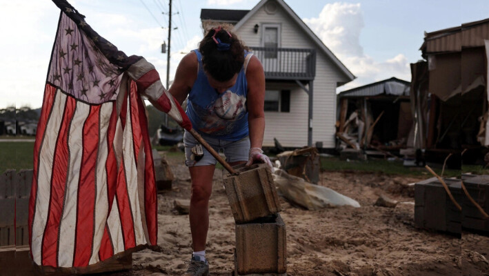 Roxanne Brooks monta una bandera estadounidense en una pila de bloques de hormigón frente a la casa móvil destruida de su amiga (R) tras las inundaciones provocadas por el huracán Helene en Swannanoa, Carolina del Norte, el 6 de octubre de 2024. (Mario Tama/Getty Images). 