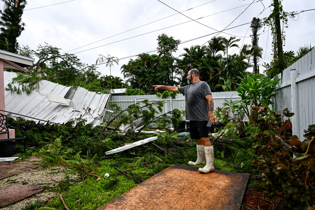 Dan Jones señala un tejado destruido en su patio trasero tras el paso de un tornado provocado por el huracán Milton, en Fort Myers, Florida, el 9 de octubre de 2024, mientras se acercaba la tormenta. Muchos residentes de Florida huyeron, pero algunos se quedaron, en las últimas horas del 9 de octubre de 2024 (Chandan Khanna/AFP vía Getty Images)