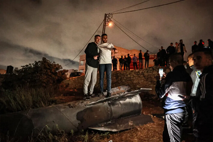 Jóvenes palestinos posan para una foto encima de un proyectil caído en Cisjordania después de que Irán lanzara una andanada de misiles contra Israel el 1 de octubre de 2024. (Zain Jaafar/AFP vía Getty Images)