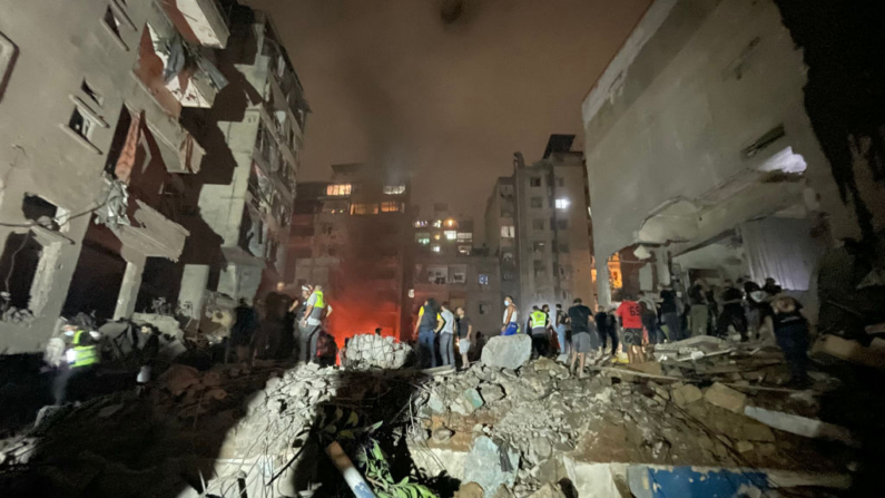 Miembros de la defensa civil libanesa y otras personas inspeccionan el lugar de un ataque aéreo israelí contra el barrio de Basta, en Beirut, el 10 de octubre de 2024. (Hassan Fneich/ AFP vía Getty Images)