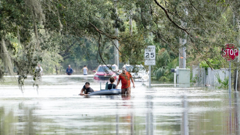 Un residente remolca un colchón de aire con gente encima por las calles inundadas a causa del huracán Milton en Tampa, Florida, el 10 de octubre de 2024. (Bryan R. Smith/AFP vía Getty Images)