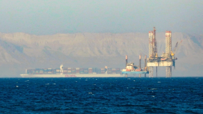 Un portacontenedores cruza una plataforma petrolífera en el Golfo de Suez en dirección al Mar Rojo antes de entrar en el Canal de Suez, a las afueras de El Cairo, Egipto, el 1 de septiembre de 2020. (Amr Abdallah Dalsh/Reuters)
