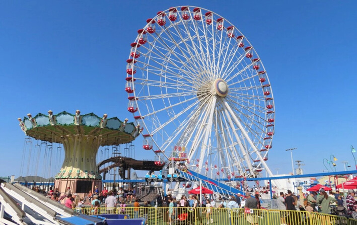 La gente se sube a la rueda gigante y a las sillas voladoras en Gillian's Wonderland, el popular parque de diversiones en el paseo marítimo de Ocean City, Nueva Jersey, durante su último día de funcionamiento antes de cerrar definitivamente, el 13 de octubre de 2024. (Wayne Parry/AP Photo)