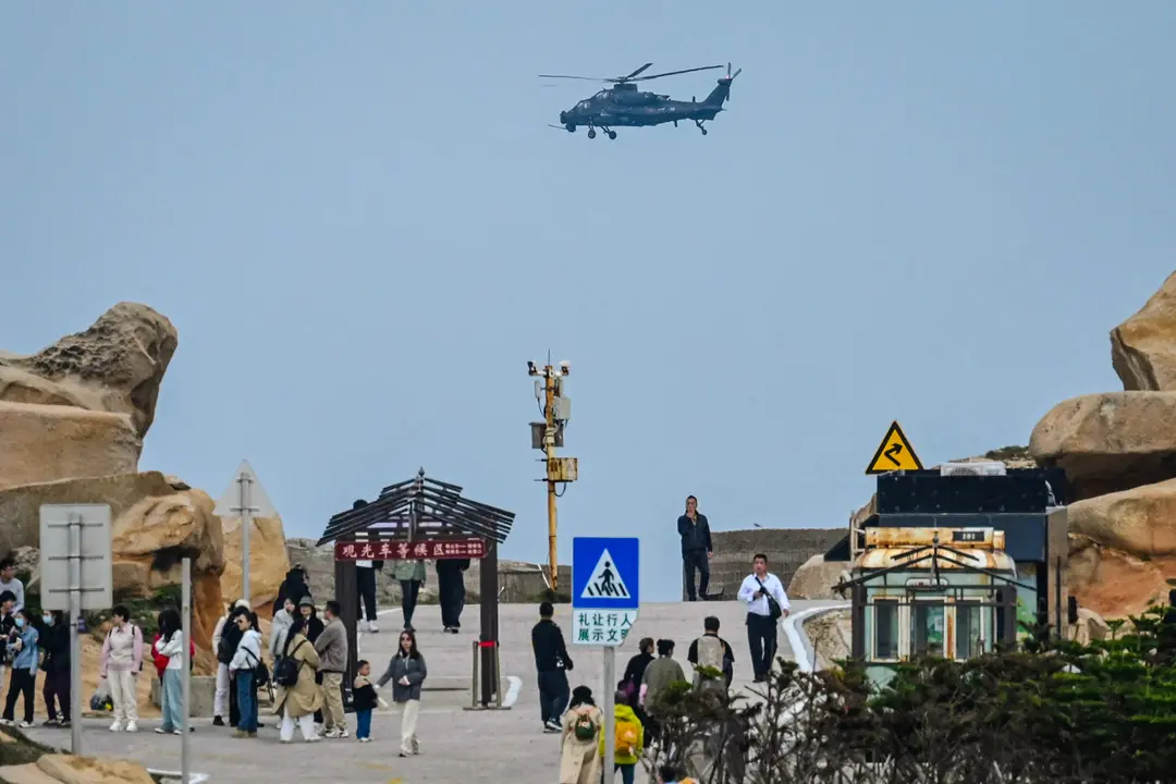 Un helicóptero militar chino sobrevuela a los turistas en un mirador sobre el estrecho de Taiwán, en la isla de Pingtan, el punto más cercano a Taiwán, en la provincia china de Fujian, el 7 de abril de 2023. (Greg Baker/AFP vía Getty Images)