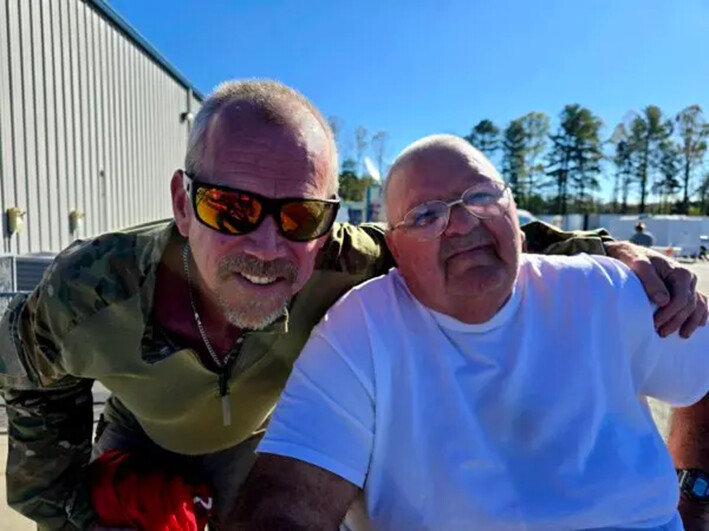 Keith Goodman (der.) y Paul Perkins disfrutan del buen tiempo en el exterior del Centro Agrícola del Oeste de Carolina del Norte, en Fletcher, Carolina del Norte, el 8 de octubre de 2024. El centro alberga actualmente a 220 desplazados supervivientes del huracán. (Allan Stein/The Epoch Times)