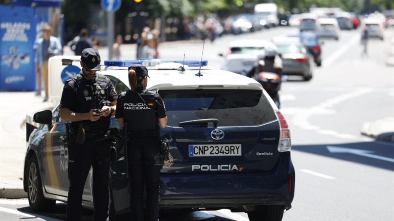 Una pareja de la Policía Nacional junto al coche patrulla en una céntrica calle de Madrid (España). EFE/Mariscal