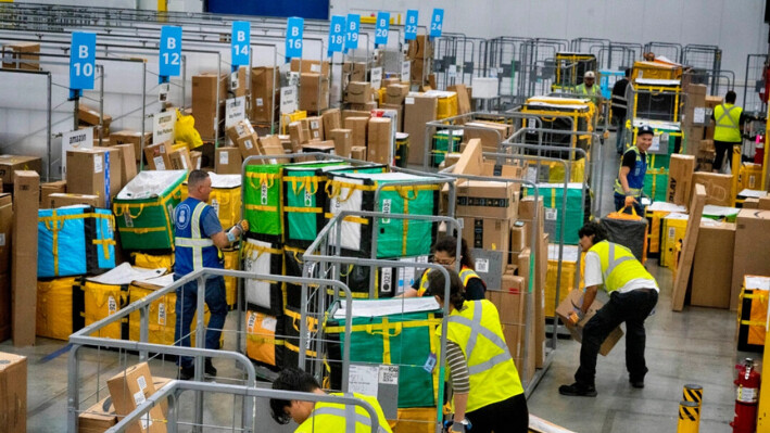 Los empleados de Amazon cargan los paquetes en carritos antes de subirlos a los camiones para su distribución, en una estación de entrega DAX7 de Amazon en South Gate, California, el 16 de julio de 2024. (Richard Vogel/AP Photo)