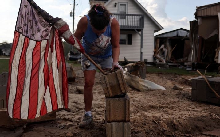 Roxanne Brooks monta una bandera estadounidense en una pila de bloques de hormigón fuera de la casa móvil destruida de su amiga (R) tras las inundaciones provocadas por el huracán Helene en Swannanoa, Carolina del Norte, el 6 de octubre de 2024. (Mario Tama/Getty Images)