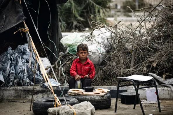 Un niño palestino come en un campamento improvisado para desplazados internos en Deir al-Balah, en el centro de la Franja de Gaza, el 17 de octubre de 2024. (Eyad Baba/AFP vía Getty Images)