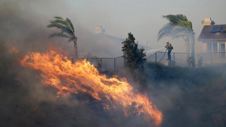 Un bombero rocía agua frente al avance de las llamas en Porter Ranch, California, el 11 de octubre de 2019. (Marcio José Sánchez/Foto AP)