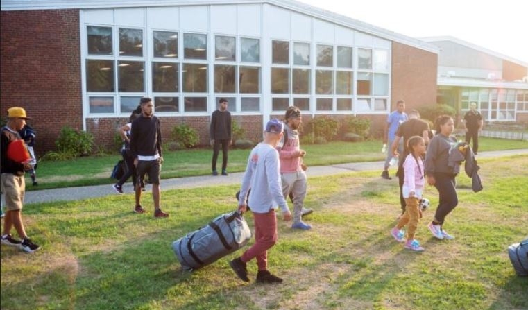 Alrededor de 50 venezolanos que cruzaron ilegalmente la frontera de Estados Unidos se encuentran en la Martha's Vineyard Regional High School en Massachusetts el 14 de septiembre de 2022, después de ser trasladados allí por el gobernador de Florida Ron DeSantis. (Ray Ewing/Vineyard Gazette vía Reuters)