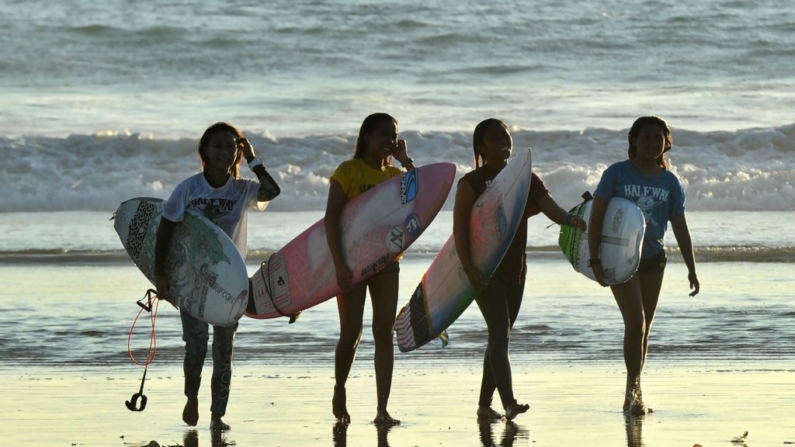 Surfistas caminan con su tabla de surf después de competir durante una competencia de surf local en la playa de Kuta en la isla turística de Bali, Indonesia, el 7 de abril de 2019. (Sonny Tumbelaka/AFP vía Getty Images)